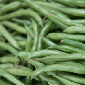 Vibrant pile of fresh organic green beans at a market stall, captured close-up for rich texture and color.