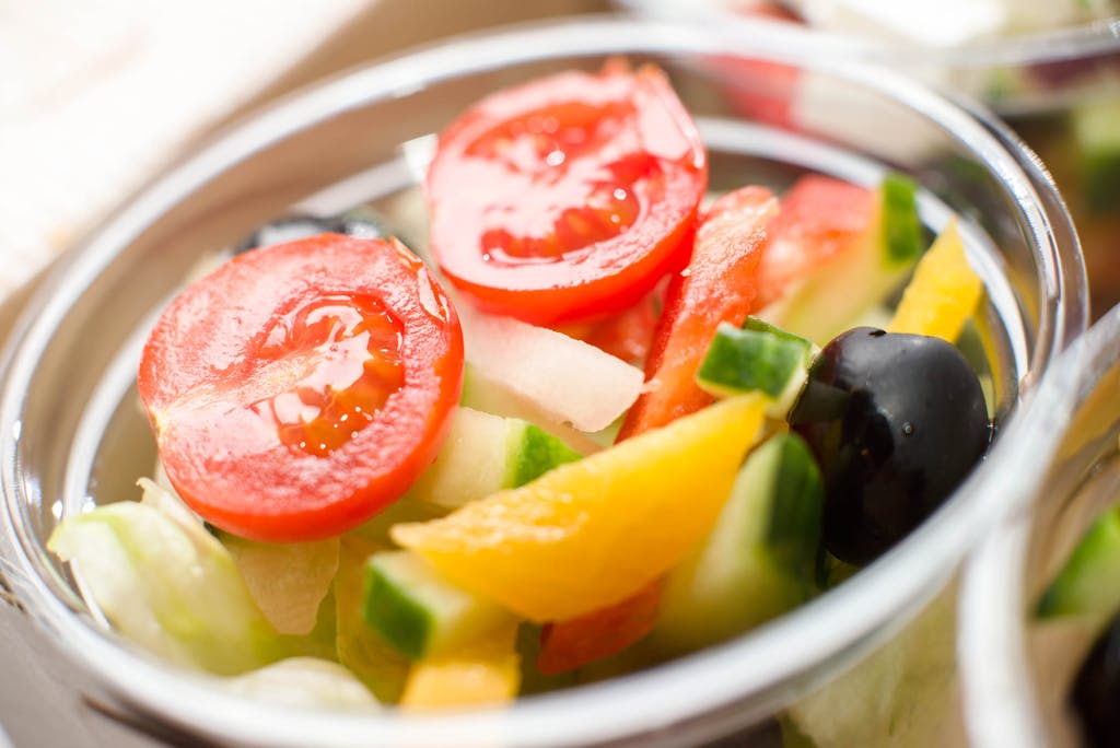 Vibrant vegetable salad with tomatoes, cucumber, and olives in a bowl. Perfect for healthy eating.